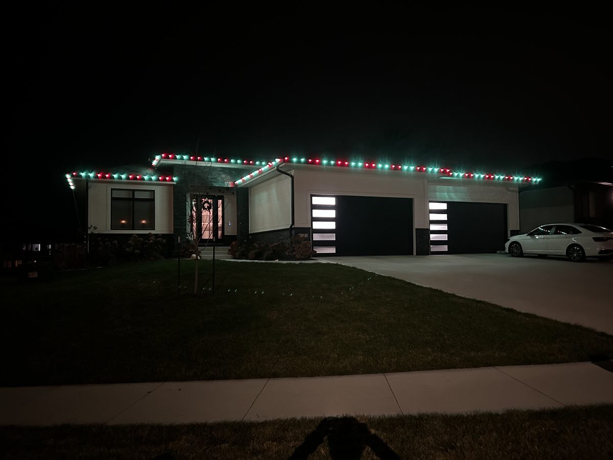 Red and green C9 bulbs alternating along the roofline of a home in the evening