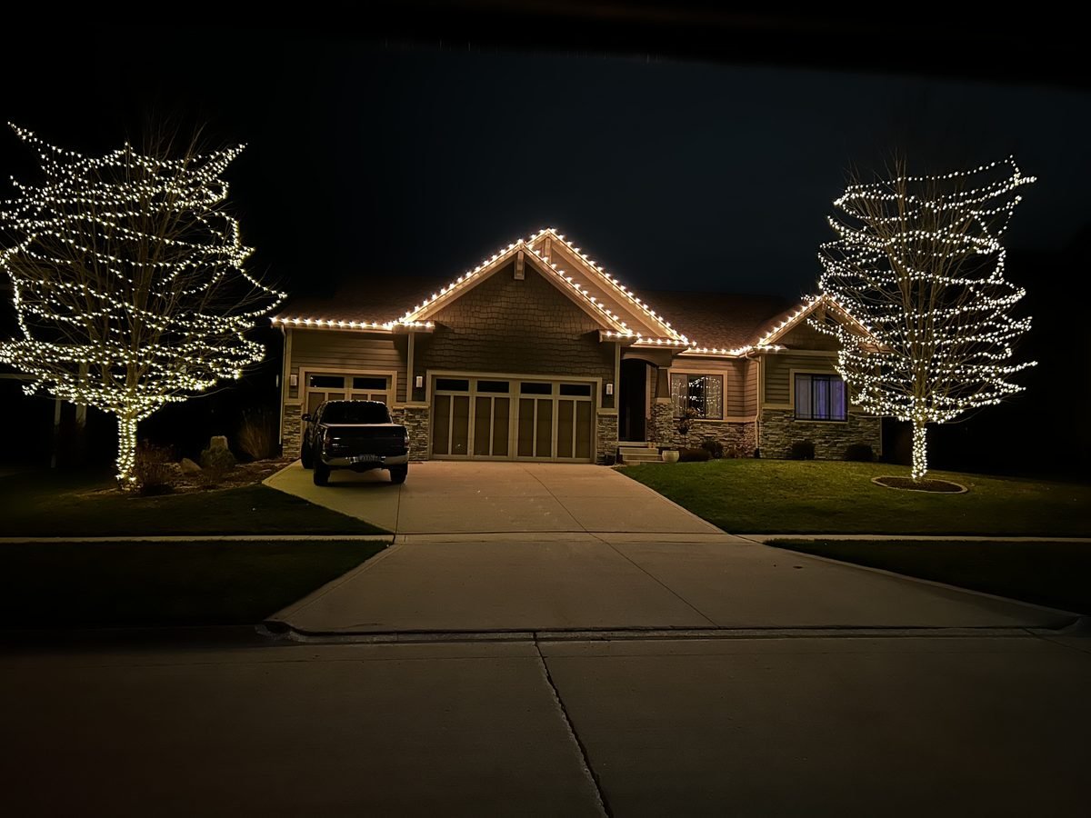 Warm white C9 bulbs running an even line along a low single story gutter and front peak at dusk