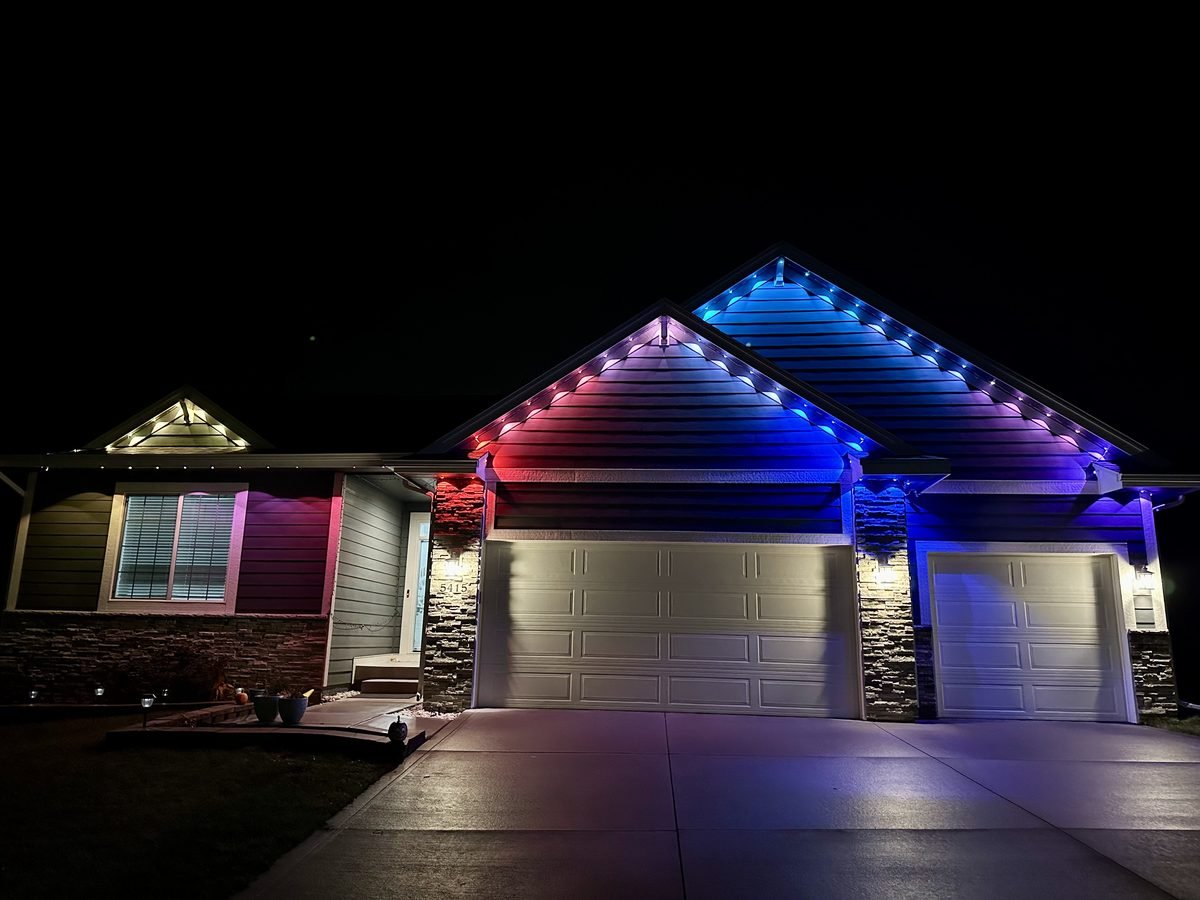 Permanent roofline lighting on a Waukee home, lit along the eaves and gables after dark